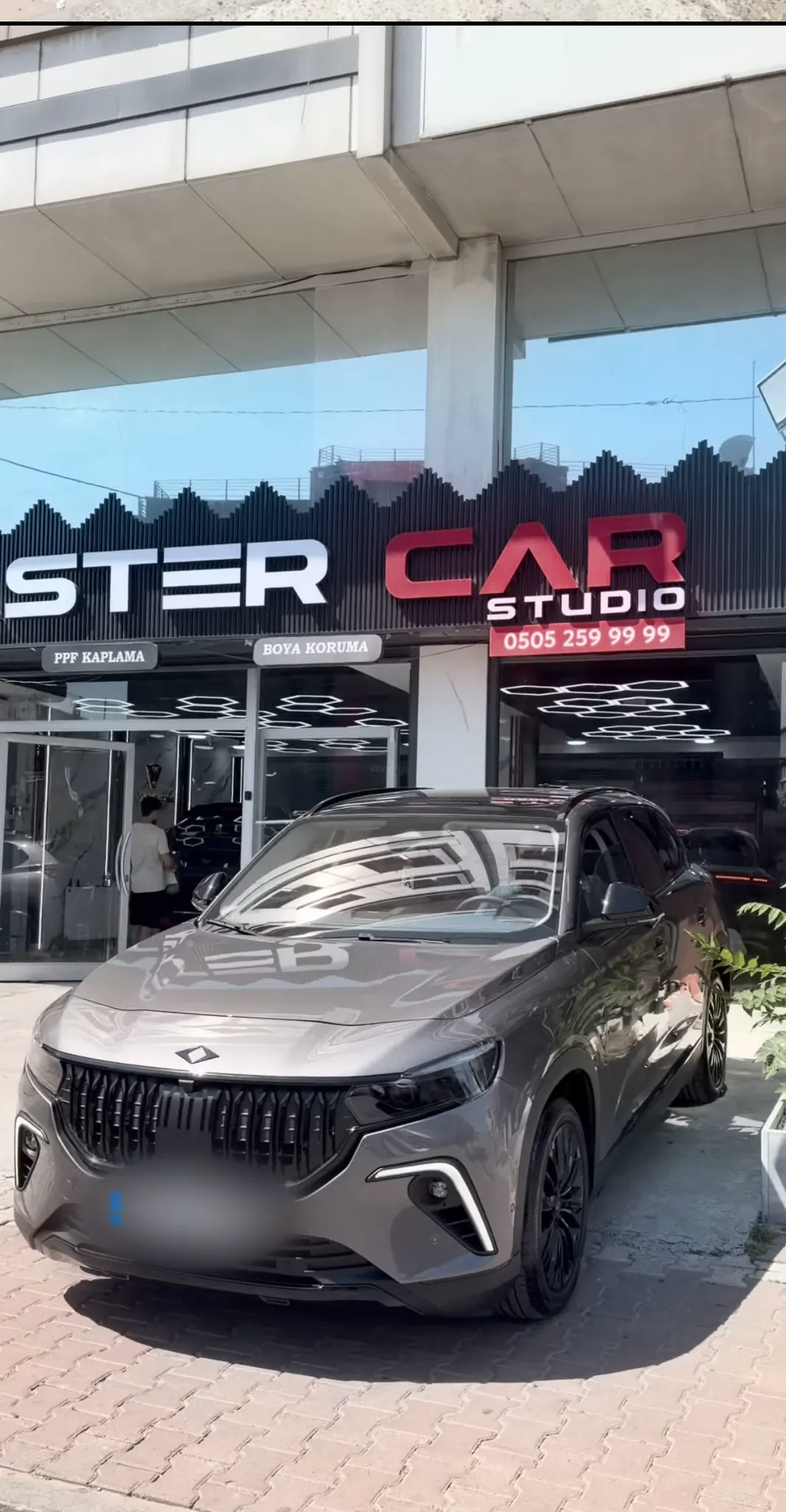 Master Car Studio tabelası önünde kaplamalı gri araç